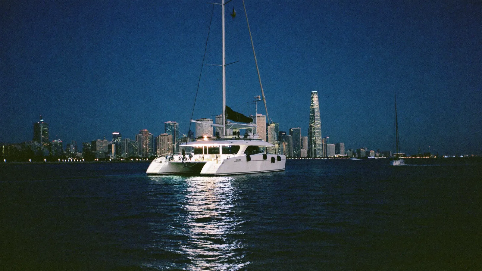 A lit party catamaran on Biscayne Bay at dusk